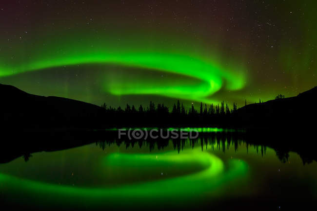 Aurora borealis reflecting in lake water at night — Stock Photo