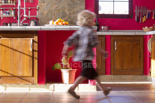 Menino correndo na cozinha — Fotografia de Stock