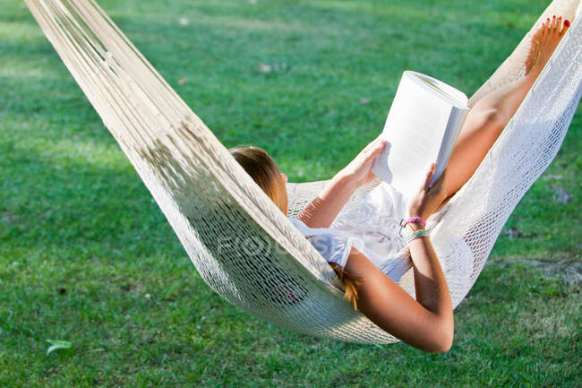 Fille lecture livre dans un hamac — Photo de stock