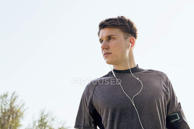 Jeune homme en plein air, vêtu de vêtements de sport et écouteurs — Photo de stock