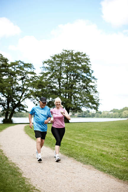 Older couple jogging together outdoors — Stock Photo