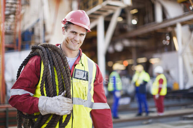 Worker carrying rope on oil rig — Stock Photo