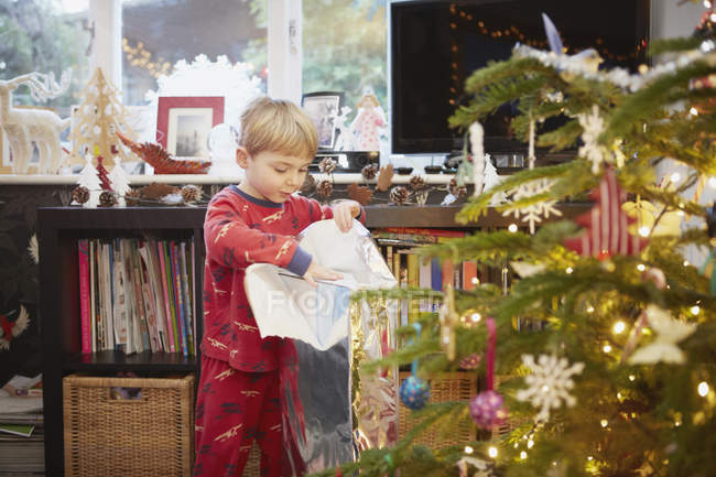 Jovem menino desembrulhando presente no Natal — Fotografia de Stock