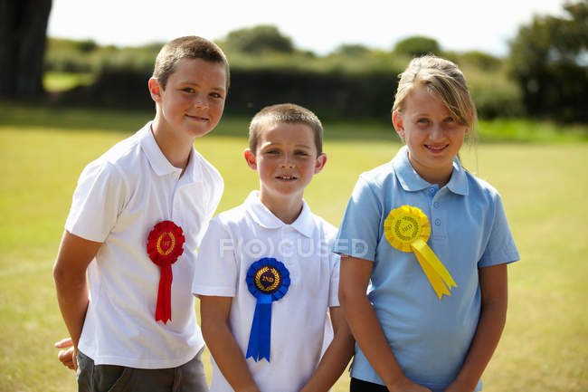 Children wearing ribbons in field, focus on foreground — Stock Photo