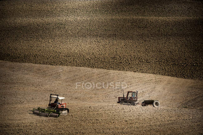 Tractor in field, Siena, Valle Orcia, Toscana, Italia - foto de stock
