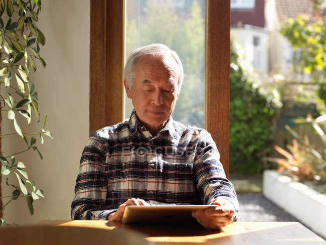 Homem mais velho usando tablet computador na mesa — Fotografia de Stock
