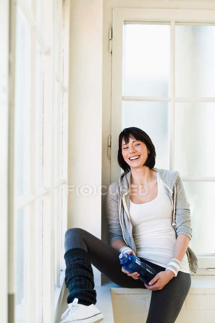 Усміхнена жінка сидить у підвіконні — стокове фото
