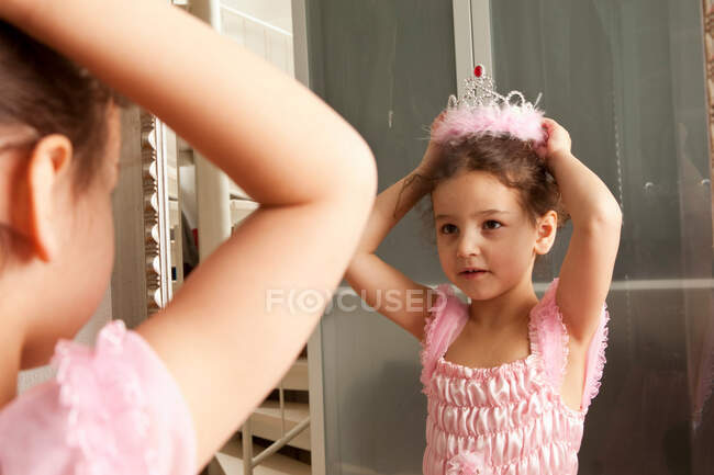Little girl putting crown on her head — Stock Photo