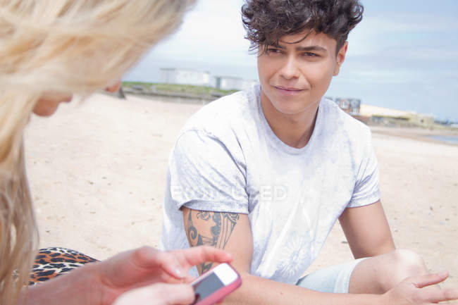 Jeune couple sur la plage avec smartphone — Photo de stock