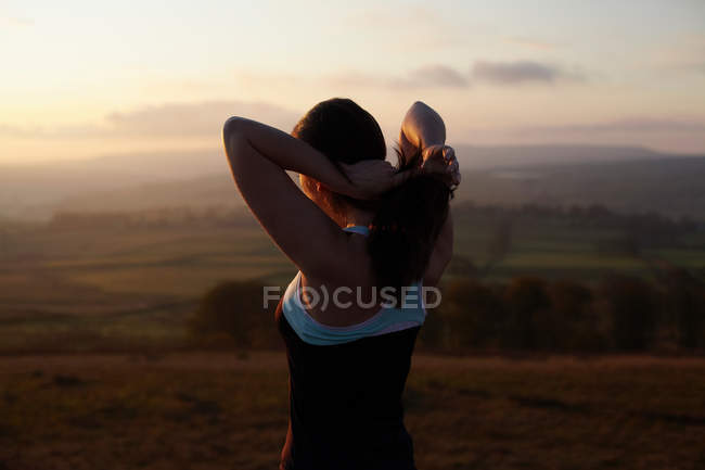 Runner tying her hair in rural landscape — Stock Photo
