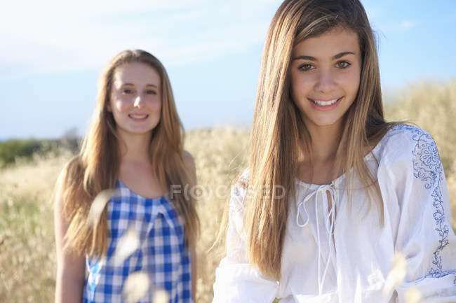 Teenage girls smiling at camera in field — Stock Photo
