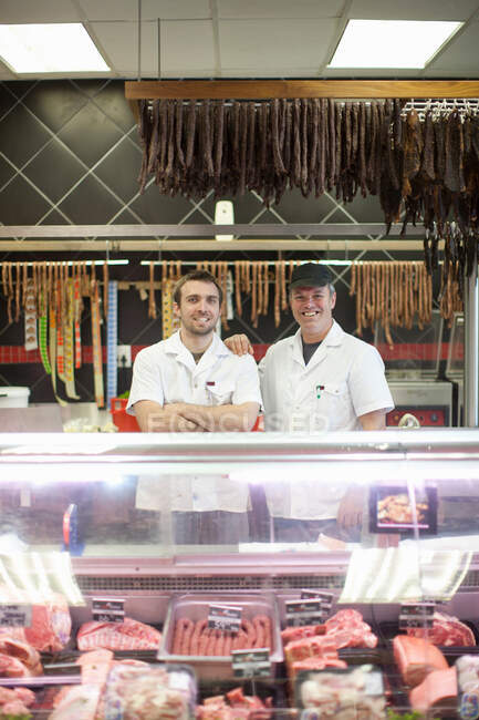 Portrait of two male butchers in shop — Stock Photo