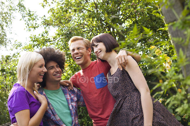 Grupo de amigos adultos jóvenes en el jardín - foto de stock