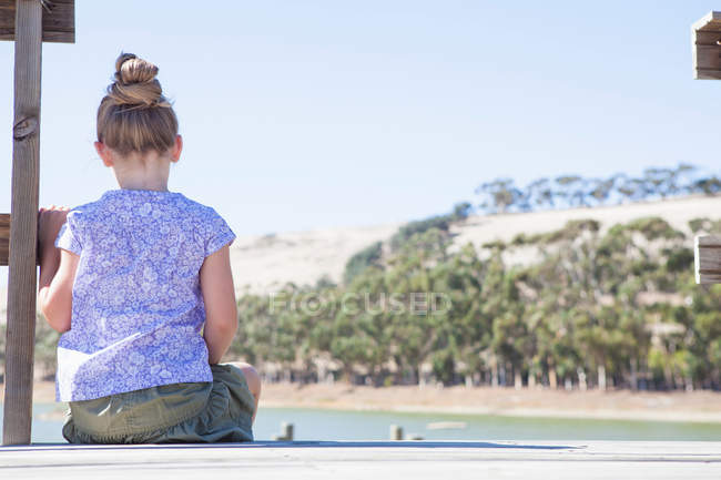 Mädchen sitzt auf Seebrücke, Rückansicht — Stockfoto