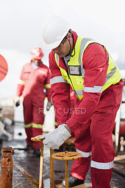 Worker turning wheel on oil rig — Stock Photo