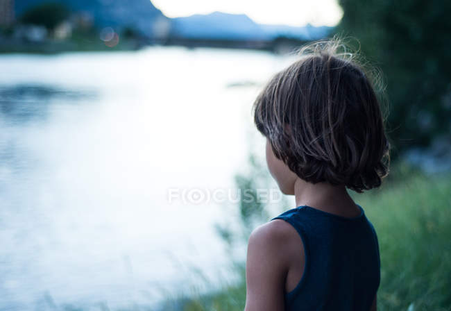 Visão traseira do menino pelo rio olhando para longe — Fotografia de Stock