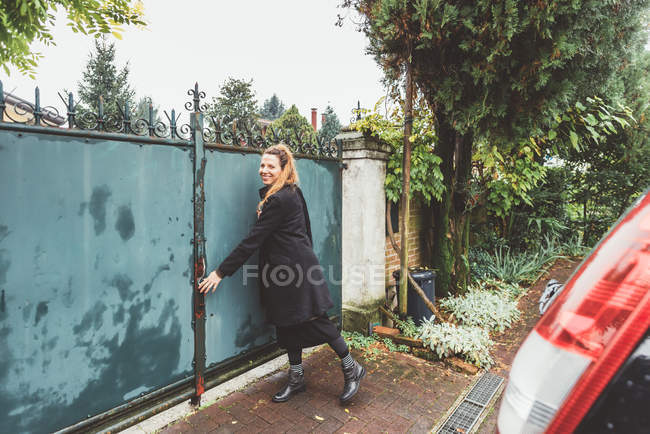 Jovem mulher fechando portões de entrada — Fotografia de Stock
