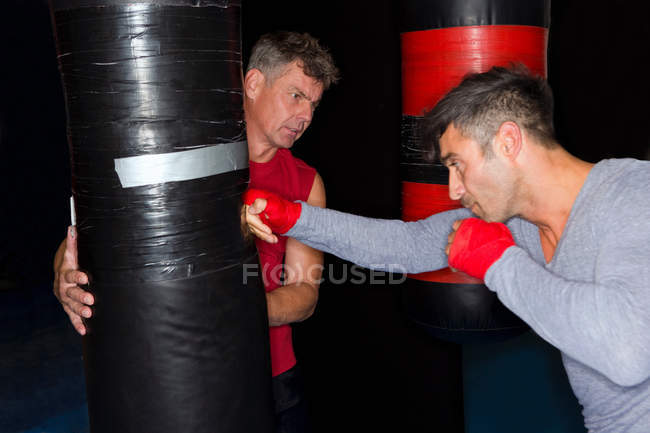Боксер работает с тренером в тренажерном зале — стоковое фото