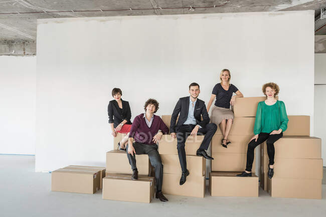 Businesspeople sitting on pile of cardboard boxes — Stock Photo