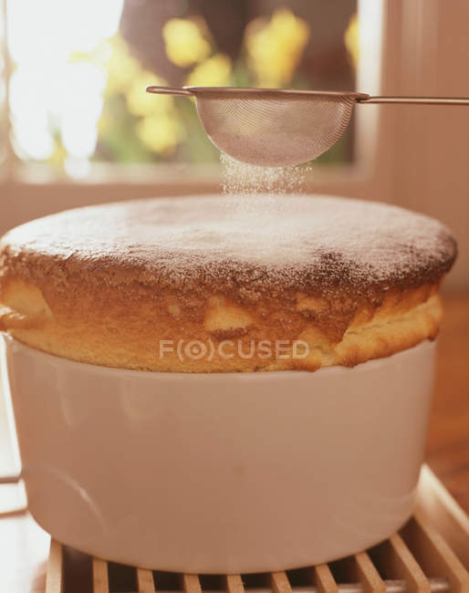 Souffle cozido no forno fresco com açúcar em pó peneirando-o — Fotografia de Stock
