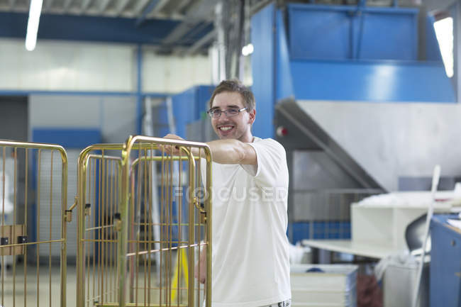 Man in launderette pushing roll cage — Stock Photo