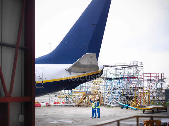 Ingenieros aeronáuticos guiando el avión 737 al hangar - foto de stock