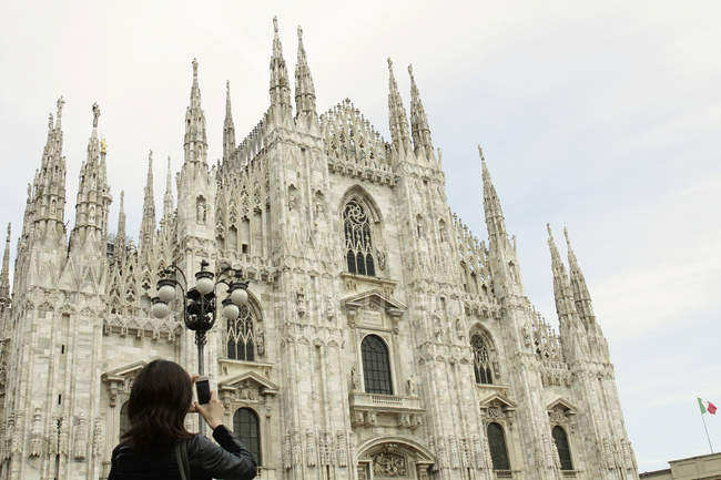 Turismo femenino fotografiando Catedral de Milán en smartphone, Milán, Italia - foto de stock
