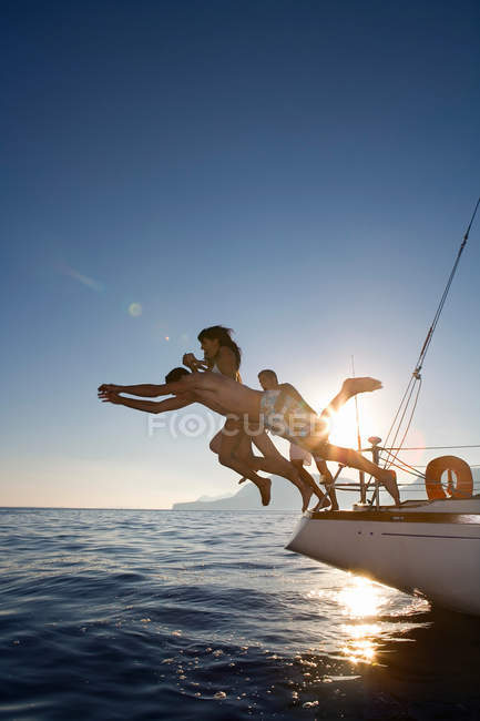 Group dive off back of sailboat — Stock Photo