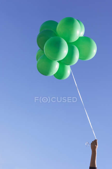 Mano sosteniendo globos verdes - foto de stock