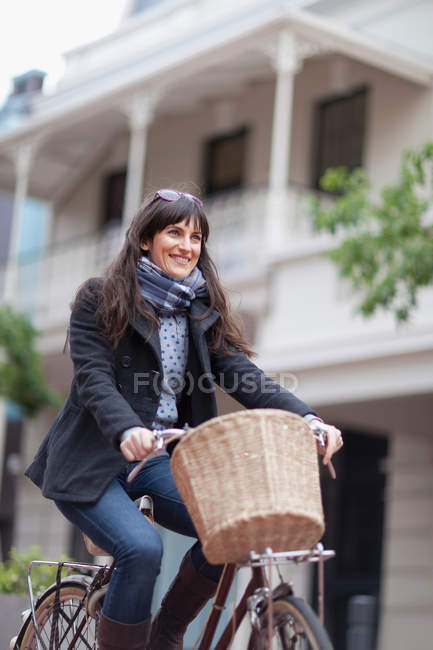 Woman riding bicycle on city street — Stock Photo