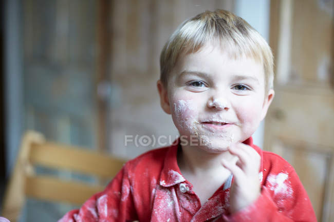 Cara de niño cubierta de harina en la cocina - foto de stock