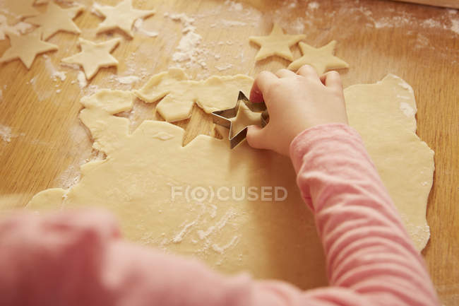 Over shoulder cropped view of girl making star shape pastry at kitchen table — Stock Photo