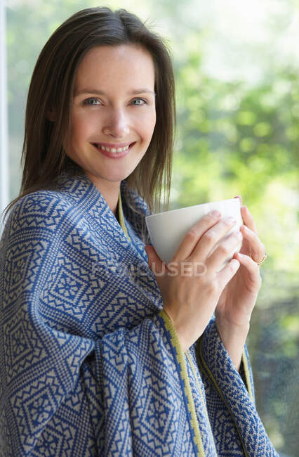 Donna con una tazza, sorridente alla macchina fotografica — Foto stock