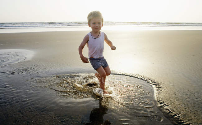 Bambino che gioca in acqua in spiaggia — Foto stock