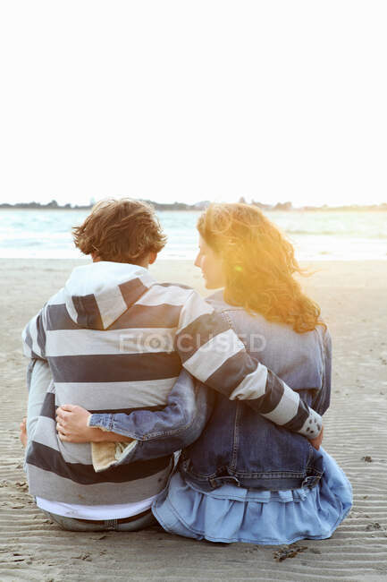 Una pareja observando la puesta de sol en una playa - foto de stock