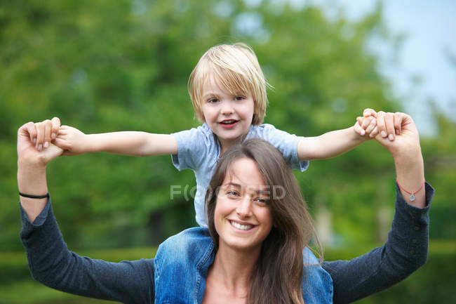 Mother carrying son on shoulders, focus on foreground — Stock Photo