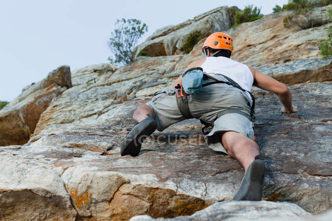 Escalador escalando empinada cara de roca - foto de stock