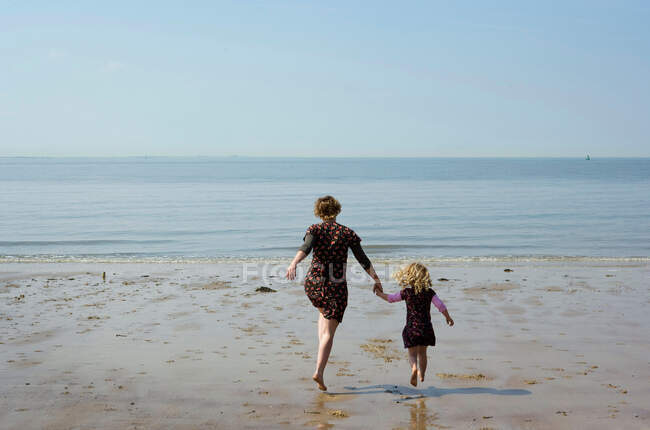 Mère et fille marchant sur la plage — Photo de stock