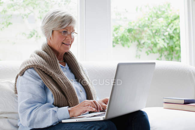 Усміхнена літня жінка використовує ноутбук — стокове фото