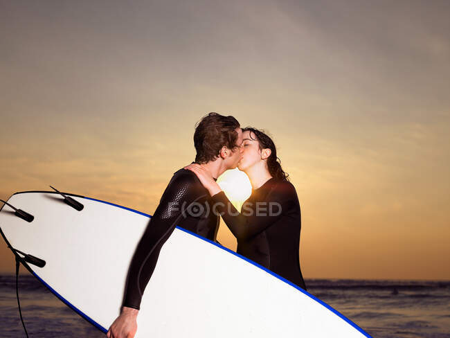 Surfer couple kissing on a beach — Stock Photo