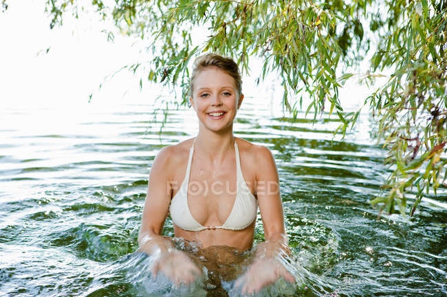 Усміхнена жінка бризкає в річці — стокове фото