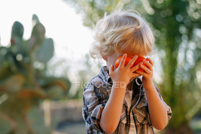 Boy playing with oranges outdoors — Stock Photo