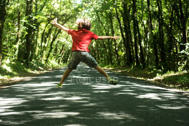 Rear view of boy jumping in mid air — Stock Photo