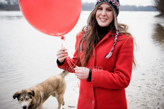 Young woman with balloon walking dog — Stock Photo
