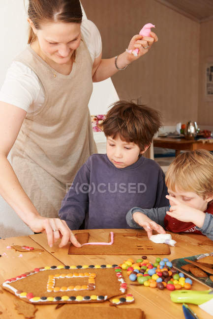 Familie schmückt Lebkuchenhaus — Stockfoto