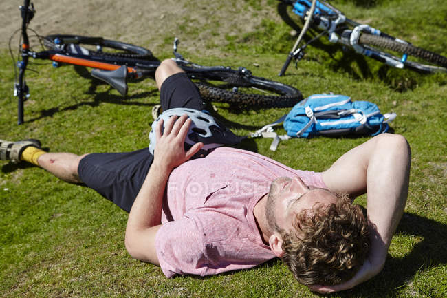 Cyclist lying down on grass by bicycle — Stock Photo