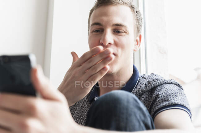 Человек, дующий в поцелуй на мобильный телефон — стоковое фото
