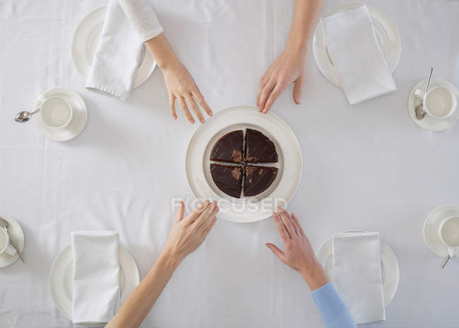 Vue de dessus des personnes atteignant les mains au dessert sur l'assiette — Photo de stock
