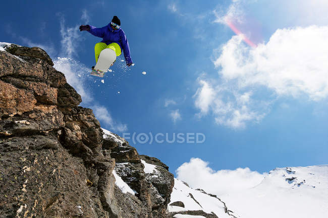 Snowboarder springt auf felsigem Hang — Stockfoto