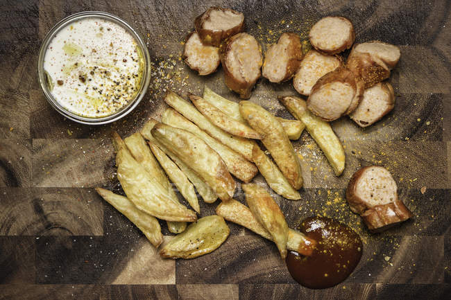 Patatine fritte, ketchup e currywurst con salse — Foto stock